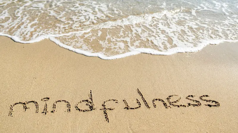 mindfulness escrito na areia da praia